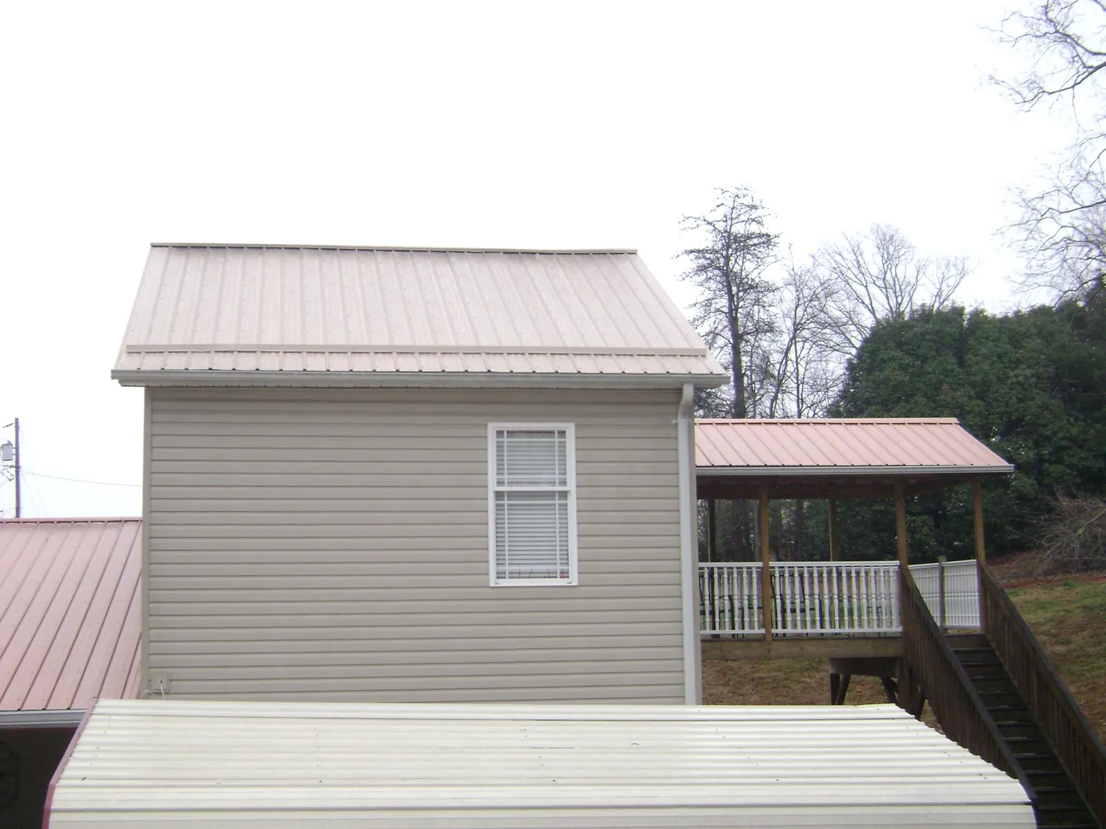 Tan metal roofs on a two story addition and attached porch, from a Roof Replacement job in Deale
