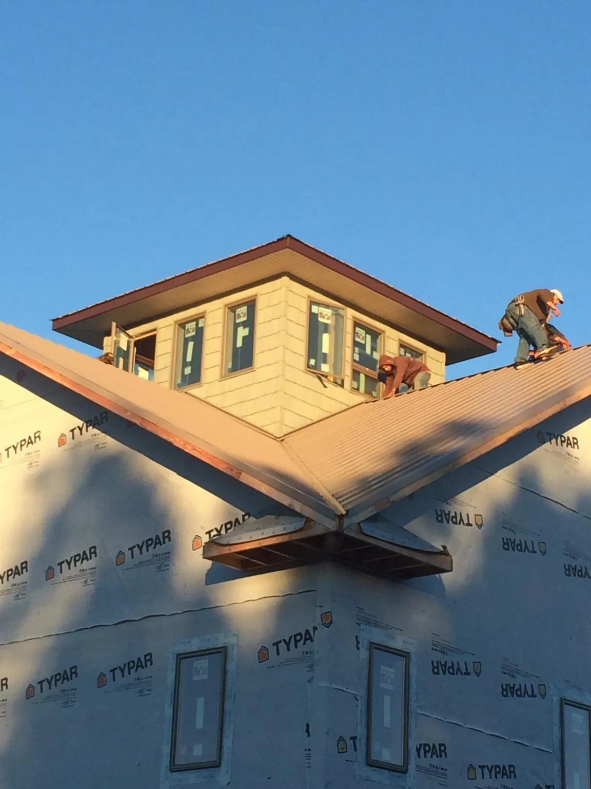 Roofers working around a rooftop cupola on a new metal roof at sunset — Roof Waterproofing in Deale by Roofing Brothers